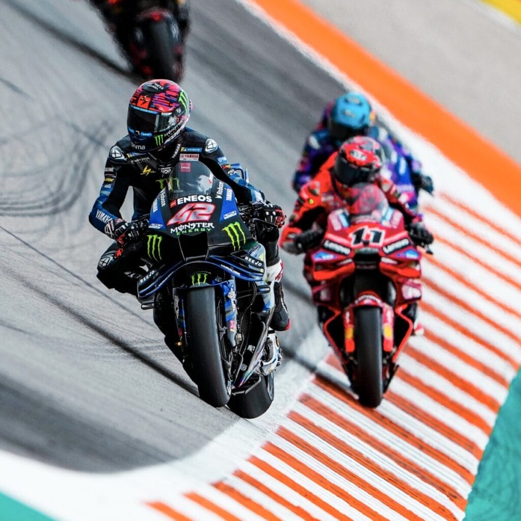 Alex Rins in pista a Valencia davanti alla Ducati di Nicolò Bulega